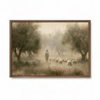 A framed landscape painting depicting a Jesus walking with a flock of sheep through a misty, tree-lined field. The artwork is rendered in soft sepia and brown tones and is presented in a dark brown wooden frame against a plain white background.